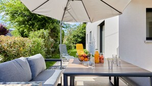 An outdoor patio with a table, chairs, and a large umbrella. - Les sablons by Interhome (Agon-Coutainville)