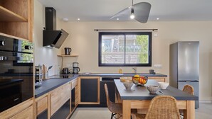 A modern kitchen with a large island, wooden cabinets, and a stainless steel refrigerator. - Les sablons by Interhome (Agon-Coutainville)