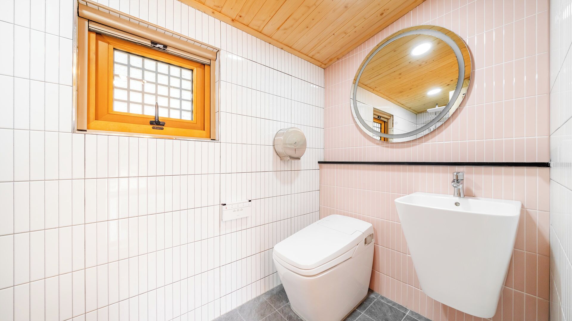 A bathroom with a toilet, sink, and a window with a wooden frame.