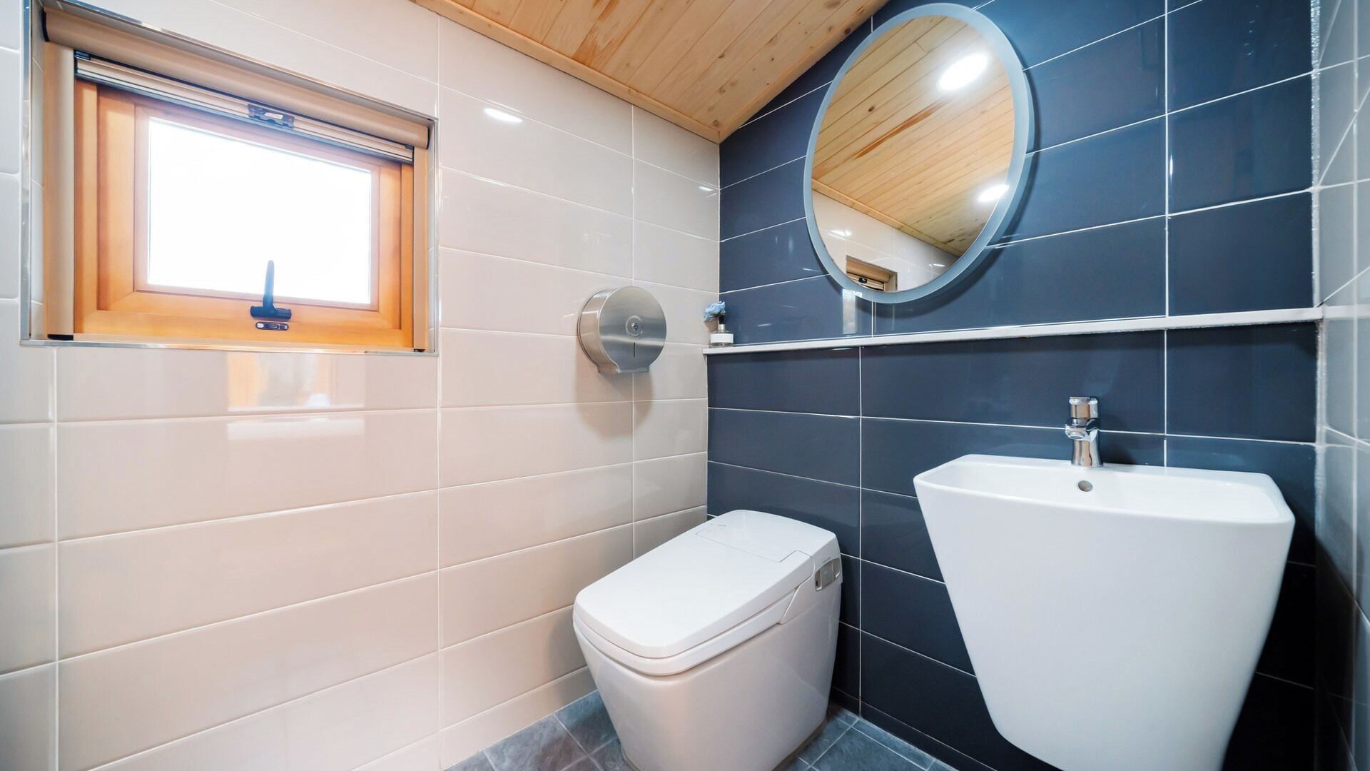 A bathroom with a toilet, sink, and a window with blinds.