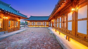 A traditional courtyard with wooden buildings, a brick pathway, and illuminated windows. - Gyeongju Ipsaedalseumeunal (Gyeongju)