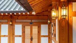A traditional wooden building with a tiled roof, wooden doors with a lattice design, and wall-mounted lanterns. - Gyeongju Ipsaedalseumeunal (Gyeongju)