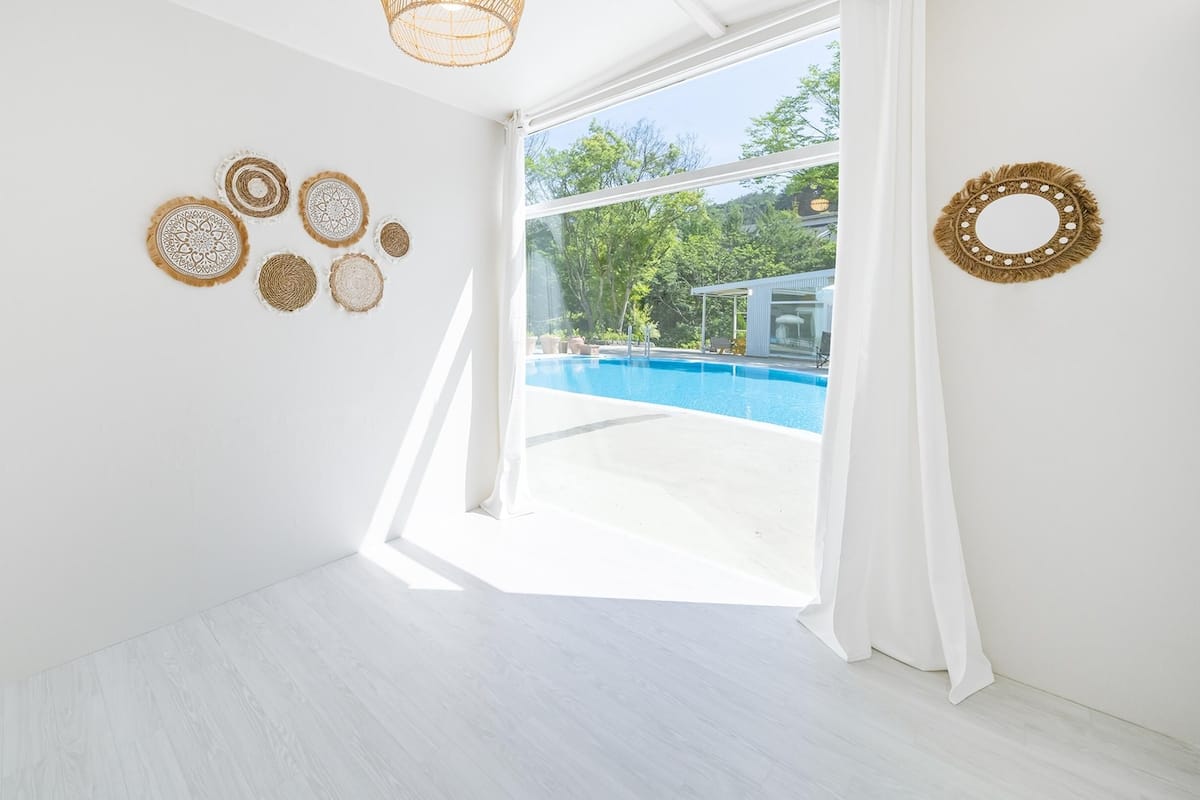 A bright room with a large window, a pool, and decorative wall art.