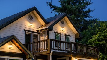Uma casa de dois andares com varanda e iluminação externa.