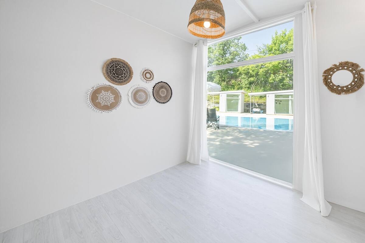 A room with a large window, white walls, and a wooden floor.