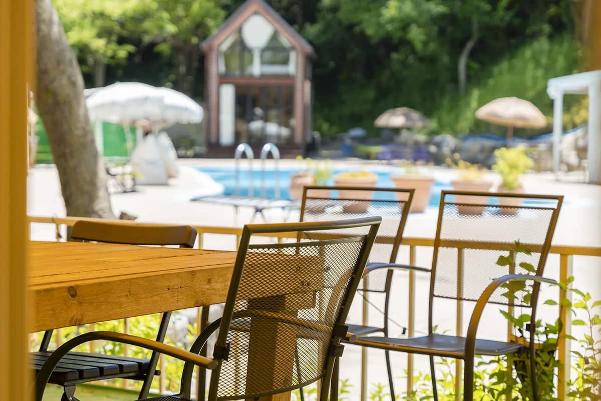 An outdoor seating area with a pool, a small building, and potted plants.