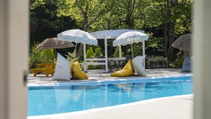 A pool area with lounge chairs and umbrellas, surrounded by trees. - Yangpyeong Seojongpool pet Pension (Yangpyeong)