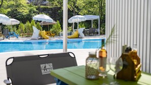 A poolside area with lounge chairs, umbrellas, and a table with bottles. - Yangpyeong Seojongpool pet Pension (Yangpyeong)