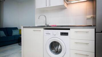 A compact kitchen with a built-in washer and dryer, white cabinets, and a small countertop.