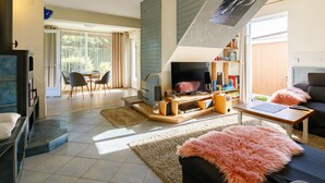 A modern living room with a fireplace, a TV, and a cozy seating area with a sofa and a chair. - Vacation home Lupo by Interhome (Balatonboglar)