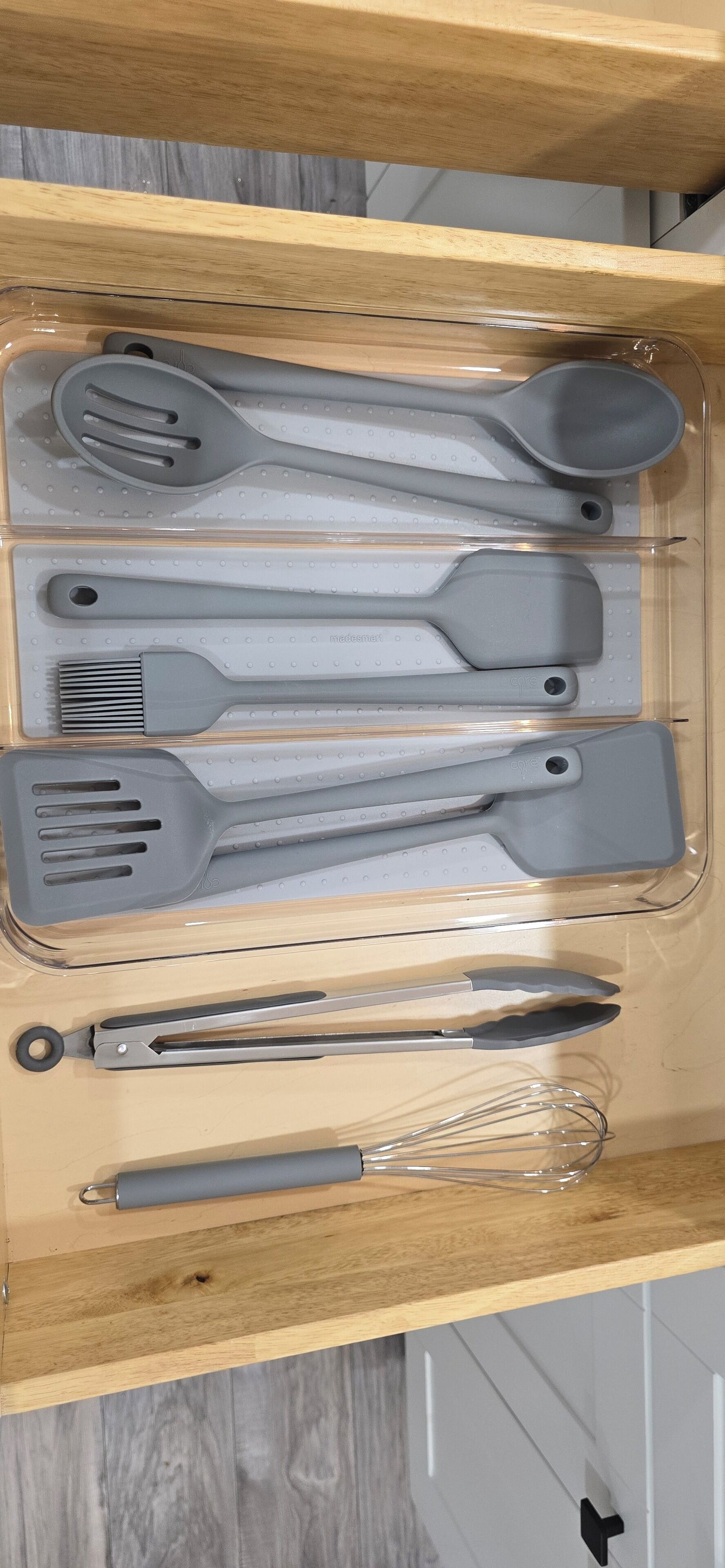 Een lade met keukengerei, zoals spatels, tangen en een garde.