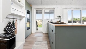 Une cuisine moderne dotée d’un grand îlot central, de meubles blancs et offrant une vue sur l’extérieur.