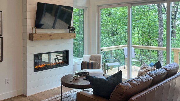 Un salon moderne doté d’une cheminée, de sièges confortables et de grandes fenêtres offrant une vue sur l’extérieur.