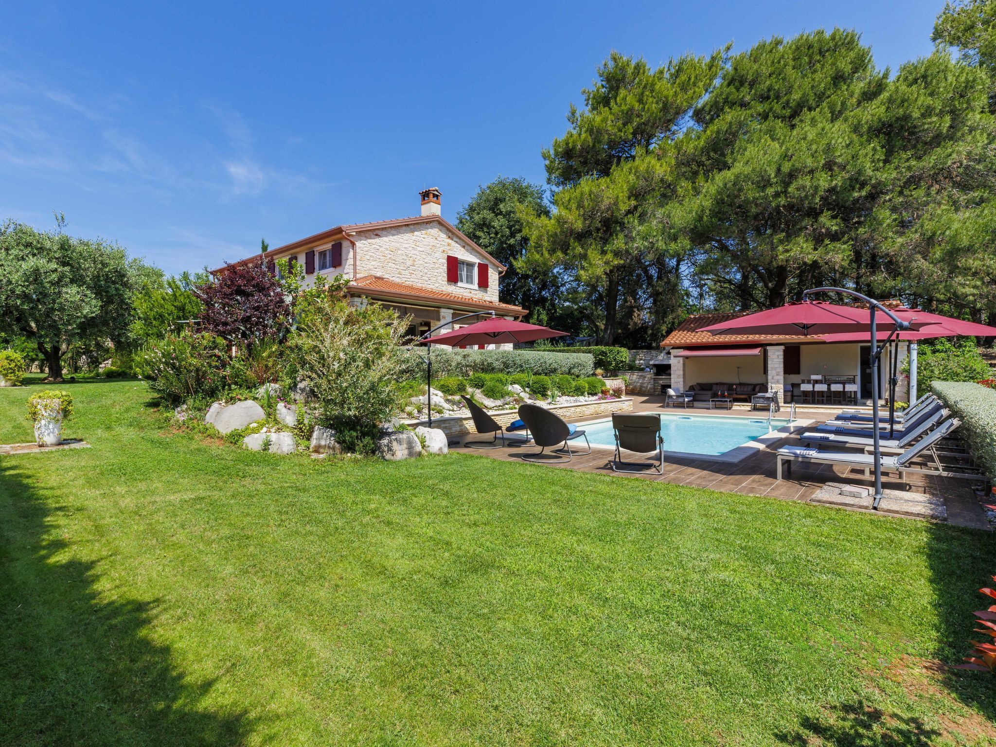 A house with a swimming pool, outdoor seating, and a garden.