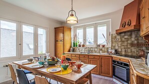 Una cocina moderna con armarios de madera, una isla central y una zona de comedor con sillas.