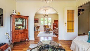 Un salón espacioso con suelos de madera, un mueble grande de madera, una mesa de centro de cristal y una lámpara de araña.