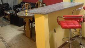 A compact living space with a kitchen area, a dining table, and a red bar stool. - Departamento Amplio Frente Parque Sarmiento 1 Cuadra a Terminal y Centro (Córdoba)