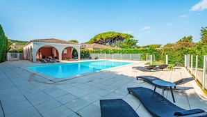 A swimming pool with lounge chairs and a covered seating area. - Le Jardin d'Artemis by Interhome (Gassin)