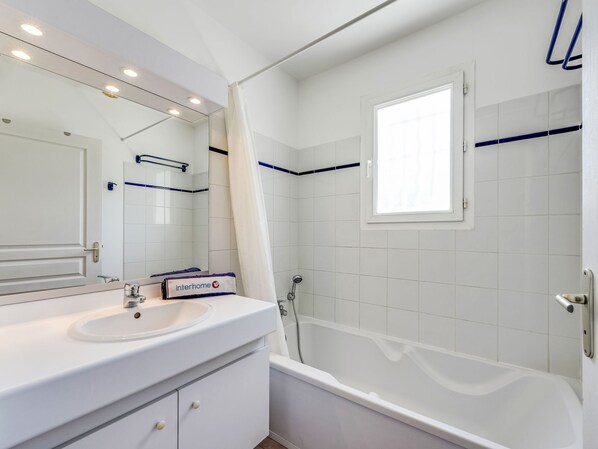 A modern bathroom with a white sink, mirror, and bathtub. - Le Jardin d'Artemis by Interhome (Gassin)