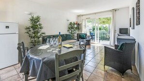 A dining area with a table set for four, a refrigerator, and a television on a stand. - Le Jardin d'Artemis by Interhome (Gassin)