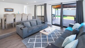 Een moderne woonkamer met een grijze bank, een salontafel en een eethoek met stoelen en een tafel.