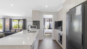 Een moderne keuken met een centraal eiland, inbouwapparatuur en uitzicht op een balkon.