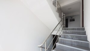 Eine moderne Treppe mit Metallgeländern und einem glänzenden Boden, die zu einem Raum mit einer dunklen Tür und einem gerahmten Bild an der Wand führt.