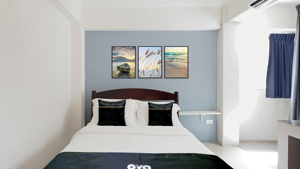 Ein Schlafzimmer mit einem Bett, einem Kopfteil, einem Nachttisch und drei an der Wand befestigten Bildern.
