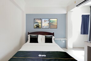 Ein Schlafzimmer mit einem Bett, einem Kopfteil, einem Nachttisch und drei an der Wand befestigten Bildern.