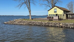 A lakeside cabin with a stone dock, a covered picnic area, and a view of the lake.