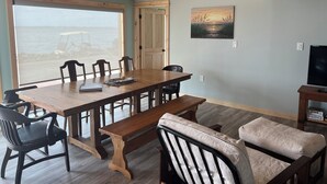 A dining area with a wooden table and chairs, a bench, and a television on a stand.