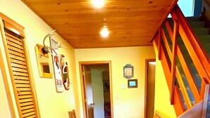 Ein gemütliches Zimmer mit Holzbalkendecke, einem Essbereich mit Holzmöbeln und einem gemusterten Teppich.