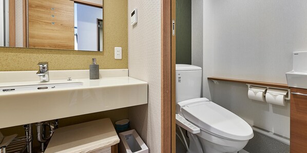 A modern bathroom with a white sink, a mirror, a toilet, and a shower area.