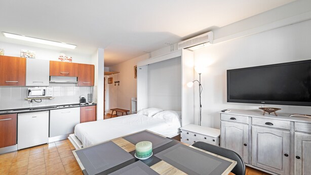 Une chambre d’hôtel compacte comprenant un coin cuisine, un lit, une tél évision et un espace repas.