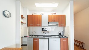 Une cuisine compacte dotée de meubles en bois, d’un four à micro-ondes, d’un lave-vaisselle et d’une machine à café.