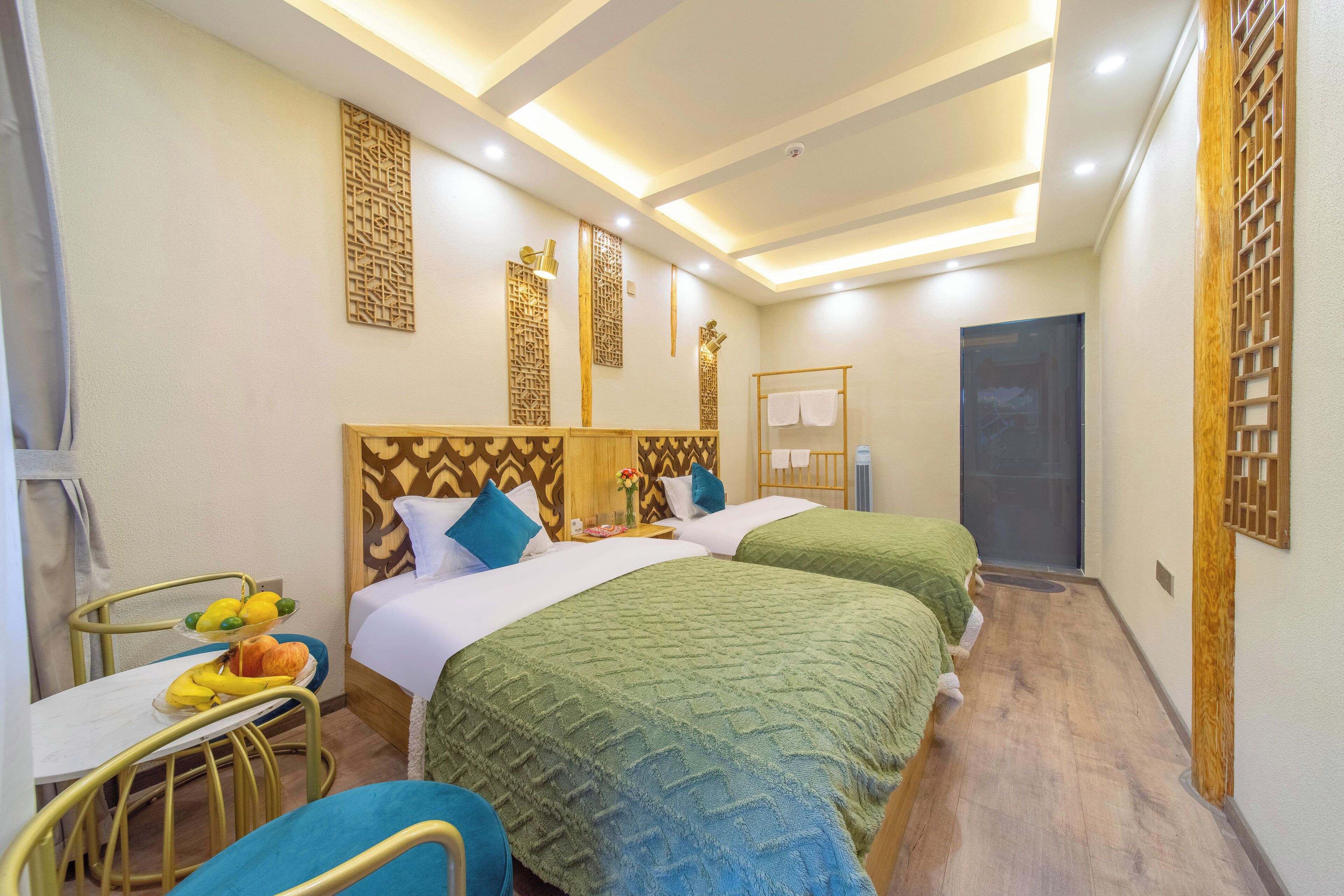 Habitación de hotel con dos camas, un escritorio con fruta y paneles decorativos en la pared.