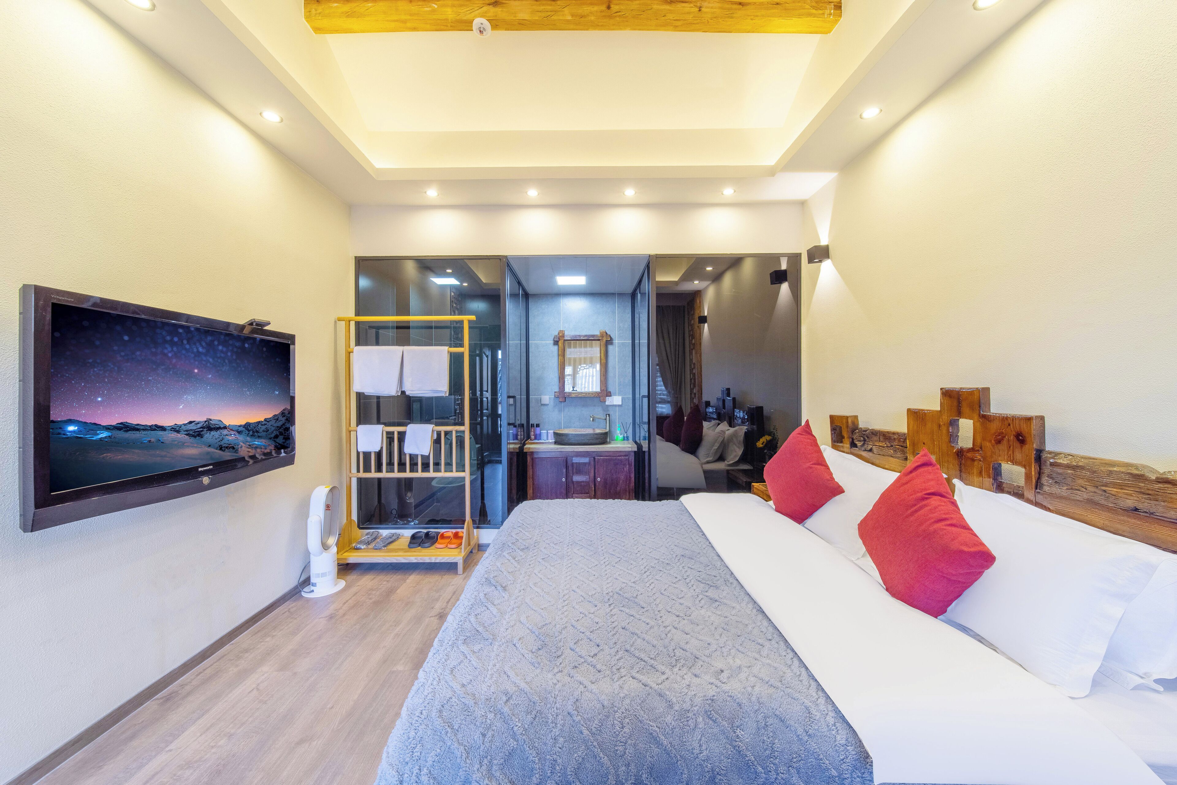 A modern hotel room with a large bed, a TV mounted on the wall, and a view into the bathroom.