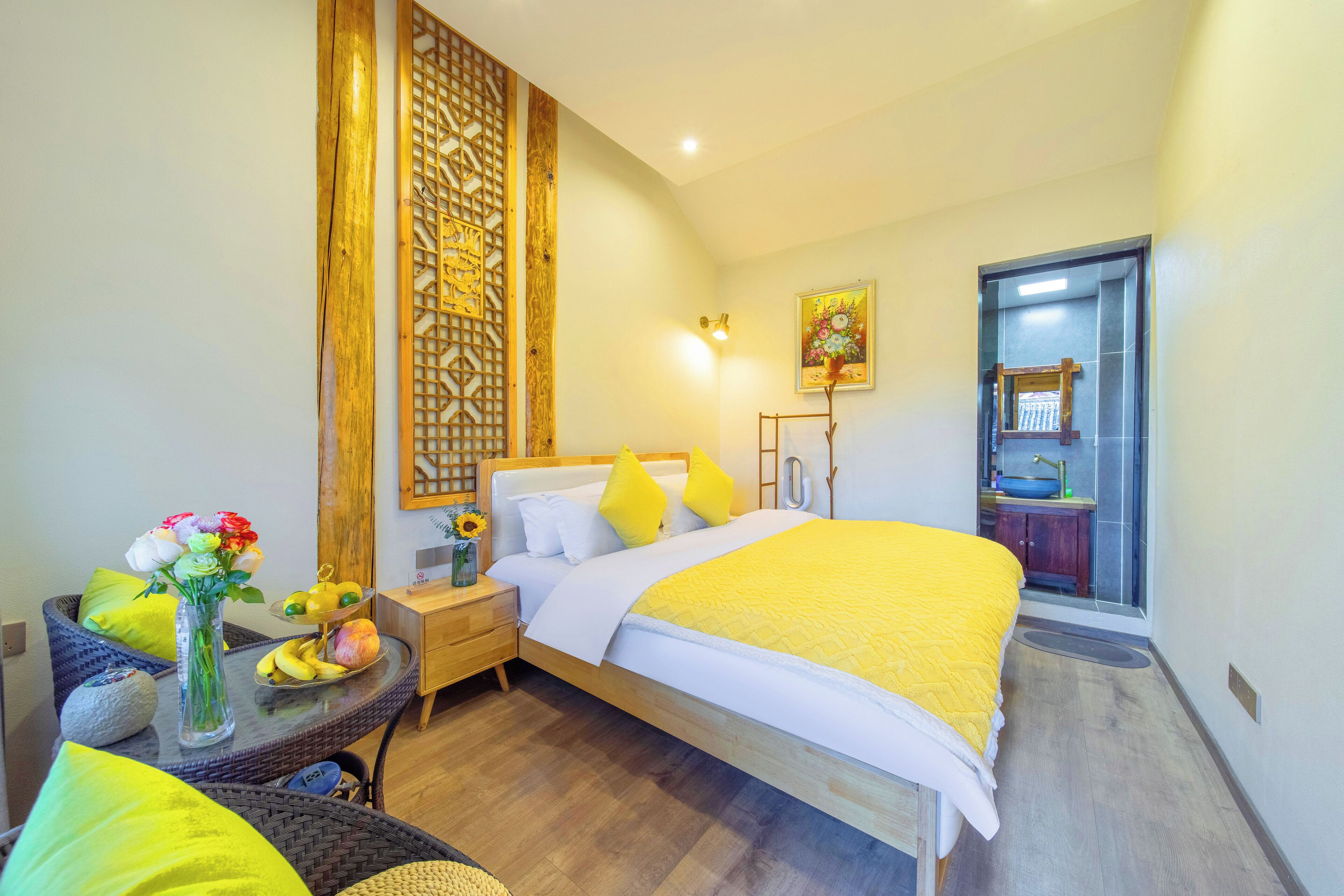 Un dormitorio con cama, mesita de noche y una pequeña mesa con flores y fruta.