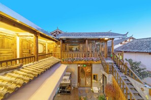 A traditional wooden building with a balcony, wooden steps, and a tiled roof. - GeGeWu (Lijiang)