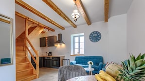 A modern kitchen with wooden beams, a dining area with a table, and a blue sofa. - Villa Lucky by Interhome (Poreč)