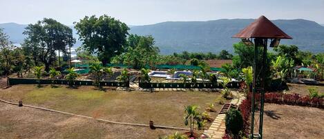 A landscaped garden with a gazebo, a swimming pool, and a view of distant mountains.