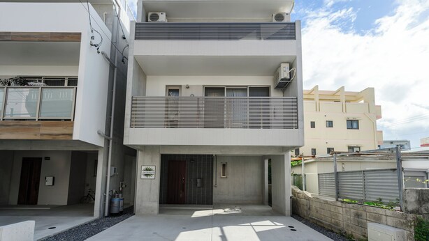 A modern two-story building with a balcony, large windows, and a concrete facade. - Araha Beachway Inn (Chatan)