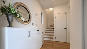 A hallway with a white cabinet, a mirror, and a staircase leading to a door. - Araha Beachway Inn (Chatan)
