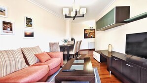 En moderne stue med sofa, sofabord, TV og spiseplads.