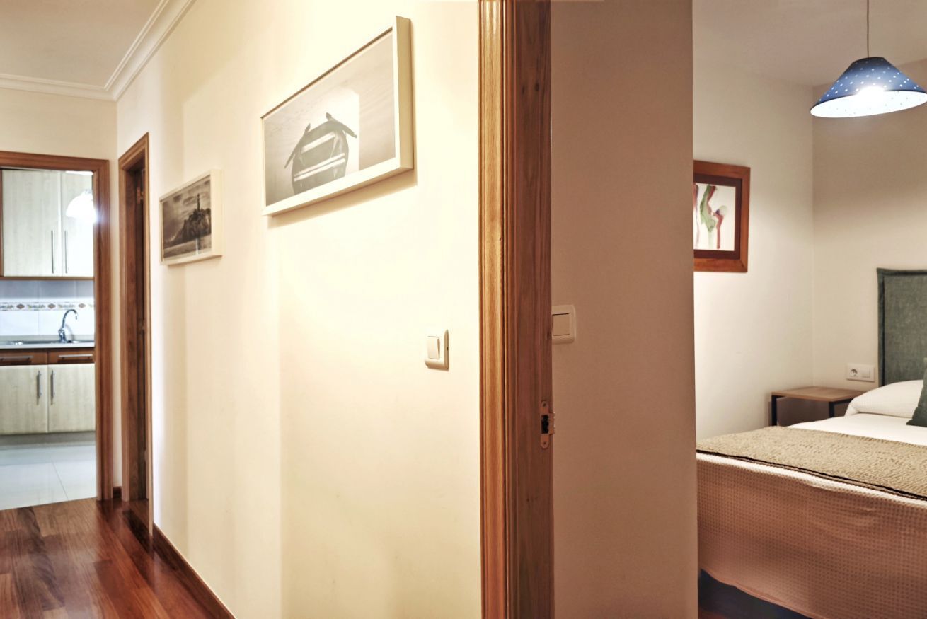 Un corridoio che conduce a una camera da letto con un letto, un comodino e una lampada a sospensione.