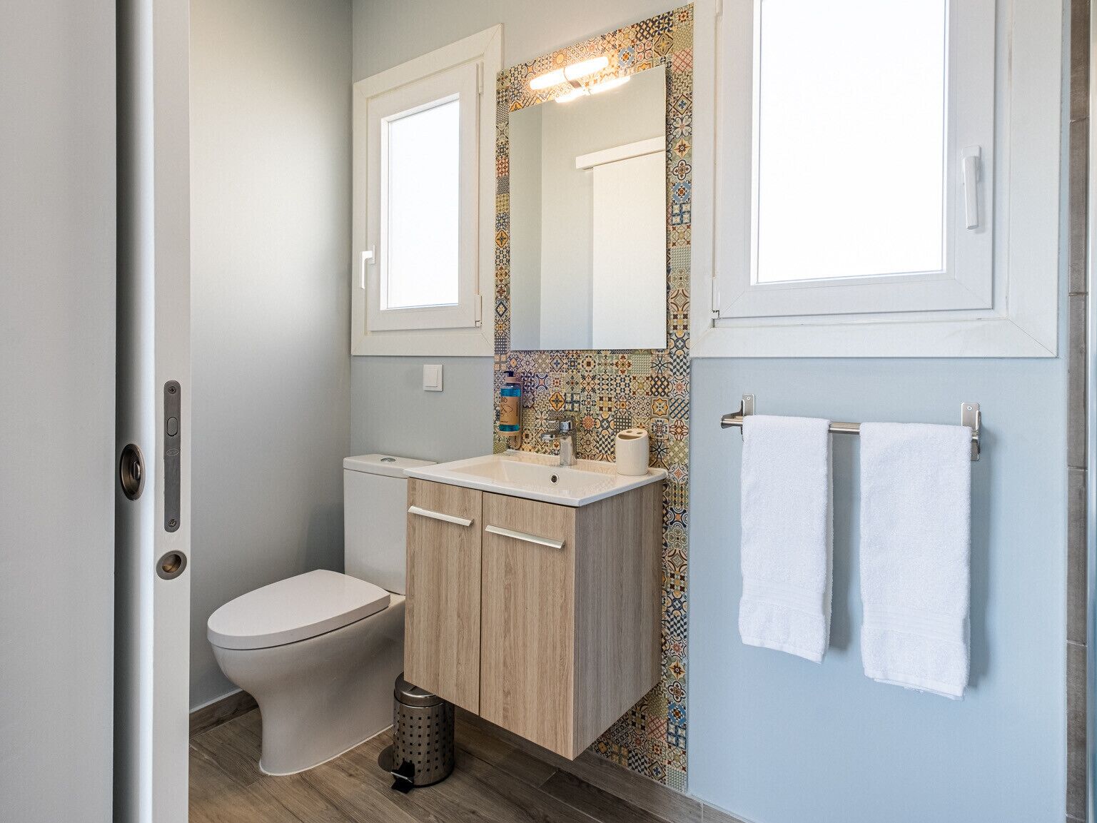 A modern bathroom with a toilet, sink, and mirror.