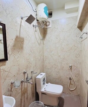 A bathroom with a toilet, a shower, and a hairdryer mounted on the wall.
