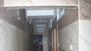 A corridor with marble walls and a striped floor, leading to a door with a dark interior. - Sundaram Residency (Chennai)