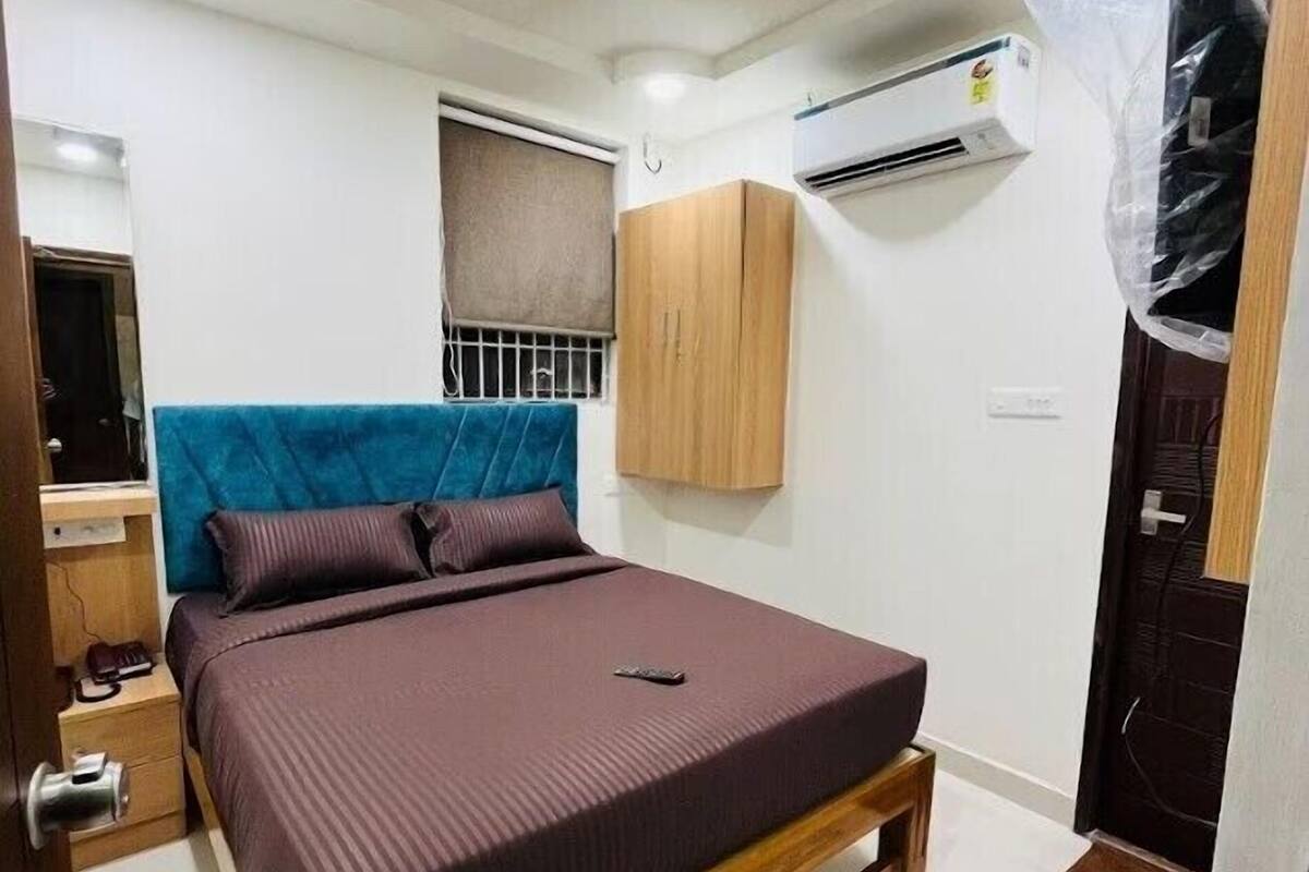 A bedroom with a bed, wooden headboard, bedside table, and a wardrobe.
