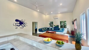 Un salon moderne avec un canapé bleu, une table basse en bois et un mur décoratif orné d’un motif représentant un poulpe.
